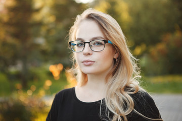 Beautiful woman in glasses on a autumn yellow background closeup portrait