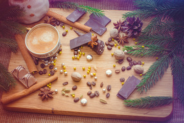 New Year's winter composition with coffee and spices in the kitchen on a wooden dinette and with pine branches. Beauty and inspiration with winter desserts.