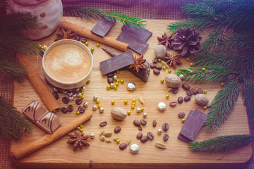 New Year's winter composition with coffee and spices in the kitchen on a wooden dinette and with pine branches. Beauty and inspiration with winter desserts.