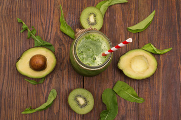 healthy green smoothie with banana, spinach, avocado and kiwi in a glass bottles on a rustic
