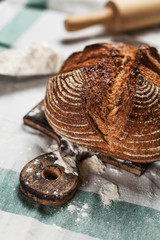 freshly baked bread and flour on a wooden board on a kitchen towel on a table