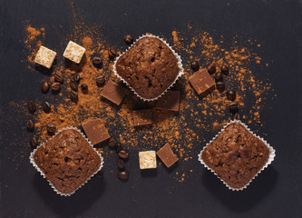 chocolate muffins on a gray surface with cocoa powder. View from above.