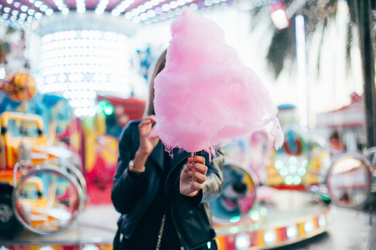 Beautiful Model Or Cute And Pretty Student Woman Holds Out Guilty Pleasure, Huge Pink Cotton Candy, Eats With Appetite With Fingers, At Festival Or Carnival During Summer Vacation Trip