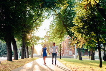 beautiful couple in love with a woman walking in a park on a bench kissing at sunset and loving each other, a blue dress and a white shirt with jeans
