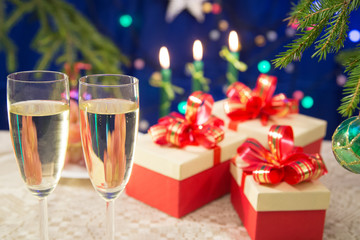 on the table glasses filled with champagne on a dark blue background with blurred lights. New Year tree. horizontal.