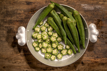 Fresh okra plant lies in a pan on a table in the kitchen