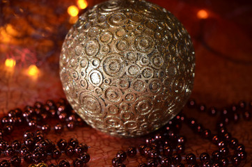Big golden ball with ornaments among red Christmas decoration composed of string of pearls