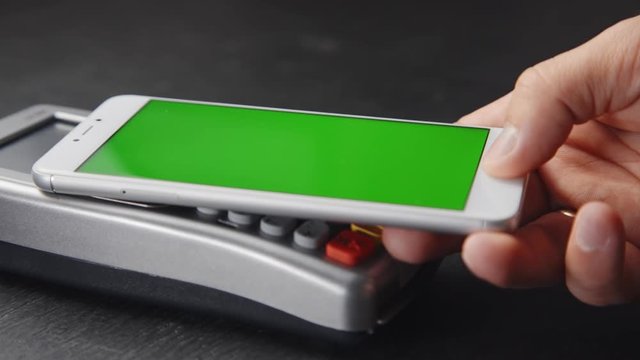 Close-up view of person using contactless payment with nfc techology. Smartphone with green screen template