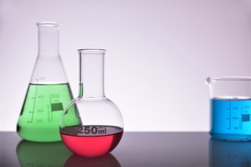 Laboratory glass chemical containers full on glass table gray background
