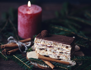 Christmas tasty cake on dark wooden background with spruce decoration. 
