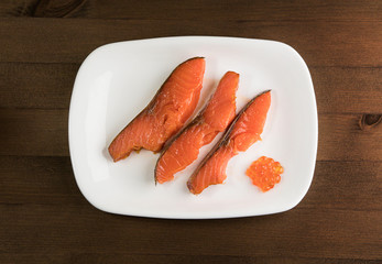 three slices of red fish and caviar on a white plate