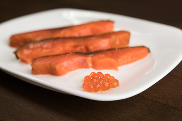 three slices of red fish and caviar on a white plate