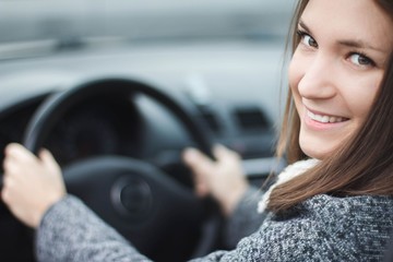 Fototapeta na wymiar Smiling young woman driving a car portrait 