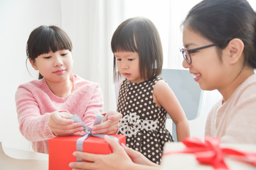Happy Asian family wrapping a gift box.