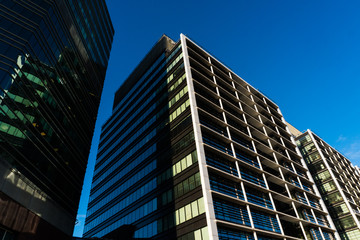 Obraz premium Tall building's glass window reflect daylight in town. Skycrappers modern building with modern glasses