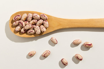 Sugar Bean legume. Healthy grains on a wooden spoon. White background.