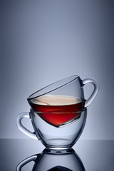 Two cups and saucers of glass. Tea is poured into the top Cup. Helium filter gives a beautiful light.