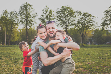 father with three children having fun in the park. hipster style. casual clothes. concept of happy...