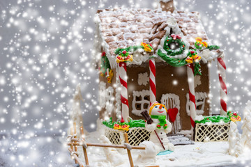 Gingerbread house, gingerbread Christmas tree and a sugar mastic snowman during snowfall