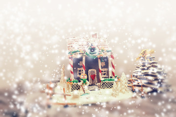 Big snow-covered gingerbread house, gingerbread Christmas tree and a sugar mastic snowman during snowfall