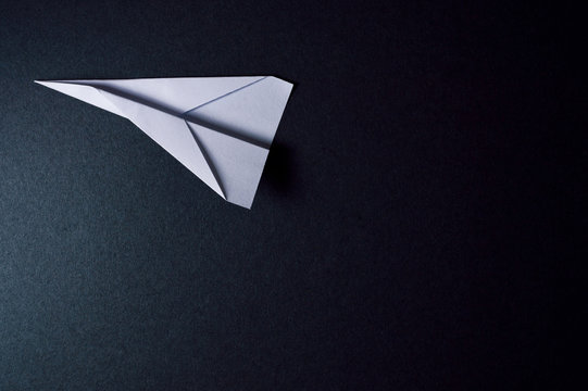 origami plane on dark background pointing to left