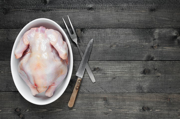 Wooden background with raw chicken in the white plate