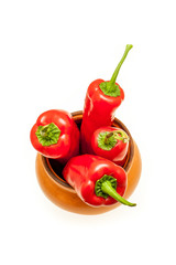 Red peppers in a brown ceramic pot  isolated on white background