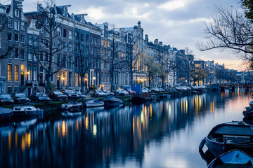 Halloween-like looking houses, canal, boats and cars during twilight blue hour, Amsterdam, Netherlands