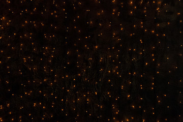 A dark wall with lights from an electric garland