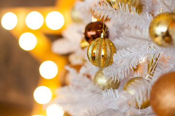 Festive blurred Christmas background with white Christmas tree, Christmas tree ornaments bokeh lights and electric garland