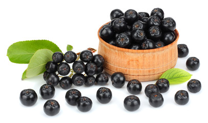 Chokeberry with leaf in wooden bowl isolated on white background. Black aronia