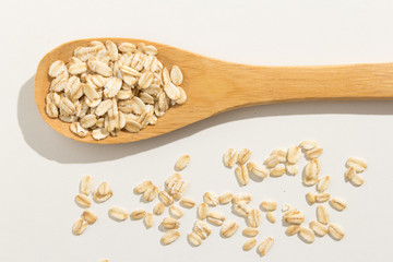 Oat cereal grain. Healthy grains on a wooden spoon. White background.