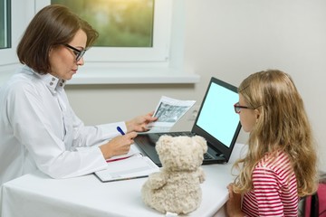Female dentist orthodontist with x-ray talking to a child.