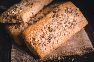 Healthy bread on burlap. Homemade whole grain fitness bread sprinkled with seeds. Closeup