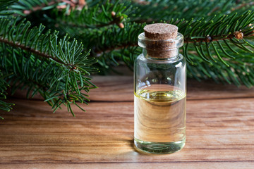Obraz na płótnie Canvas A bottle of spruce essential oil with spruce branches