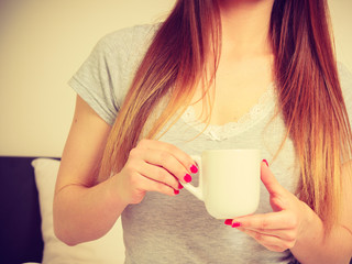 Woman holding cup of hot drink, no face