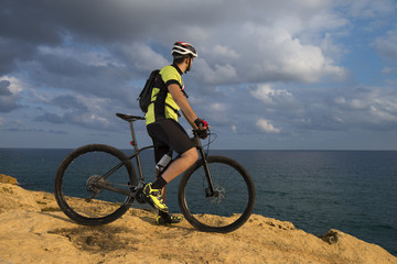 Fototapeta na wymiar mountain biker looks at the sea from the rocks