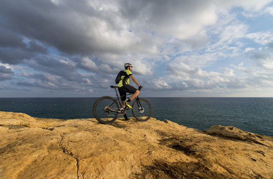 mountain biker looks at the sea from the cliff
