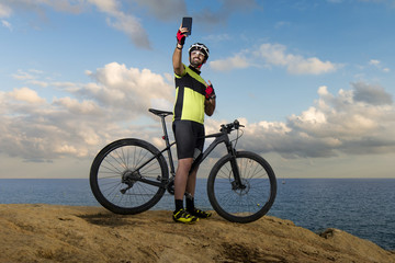 Fototapeta premium mountain biker takes photo on cliff