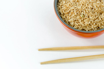 the rice in the bowl and chopsticks isolated on white background; brown rice, rice grains