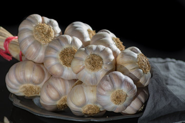 String of french pink garlic on old tin plate on black background