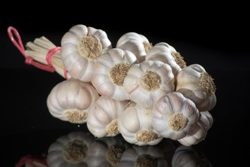String of french pink garlic on old tin plate on black background © barmalini
