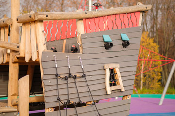 Fototapeta na wymiar Modern equipped kids playground in sunny day. Wood pirate ship