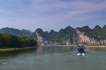 Yangshuo, China - August 1, 2010: Passenger boats with tourists in the Li River with the tall limestone peaks in the background near Yangshuo in China, Asia.