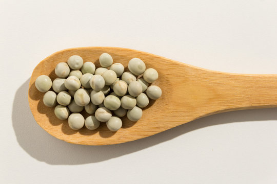 Pea. Nutritious grains on a wooden spoon on white background.