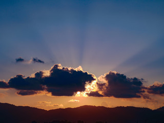 Fototapeta premium Sea and evening sky Cloud over the sun There is a beam coming out of the clouds. There is a mountain backdrop
