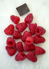 Raspberries and Chocolate Piece Scattered on a Marble Background Vertical Top View