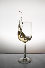 splash of white wine in a glass