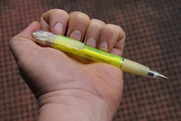зелёная ручка в руке на коричневом фоне
