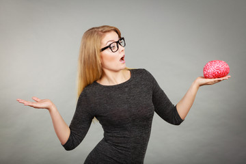 Woman in eyeglasses being confused holding brain